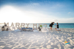 proposal with marry me sign in the sand