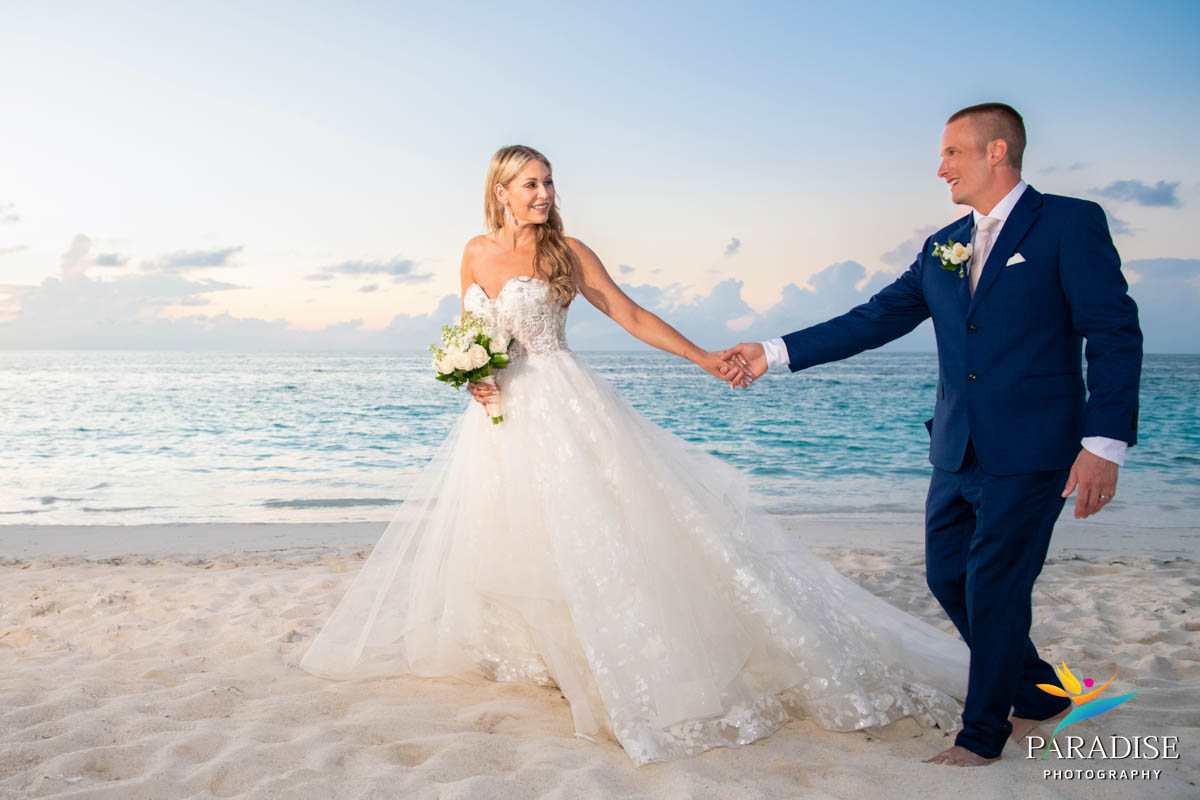 bride leads groom along the beach