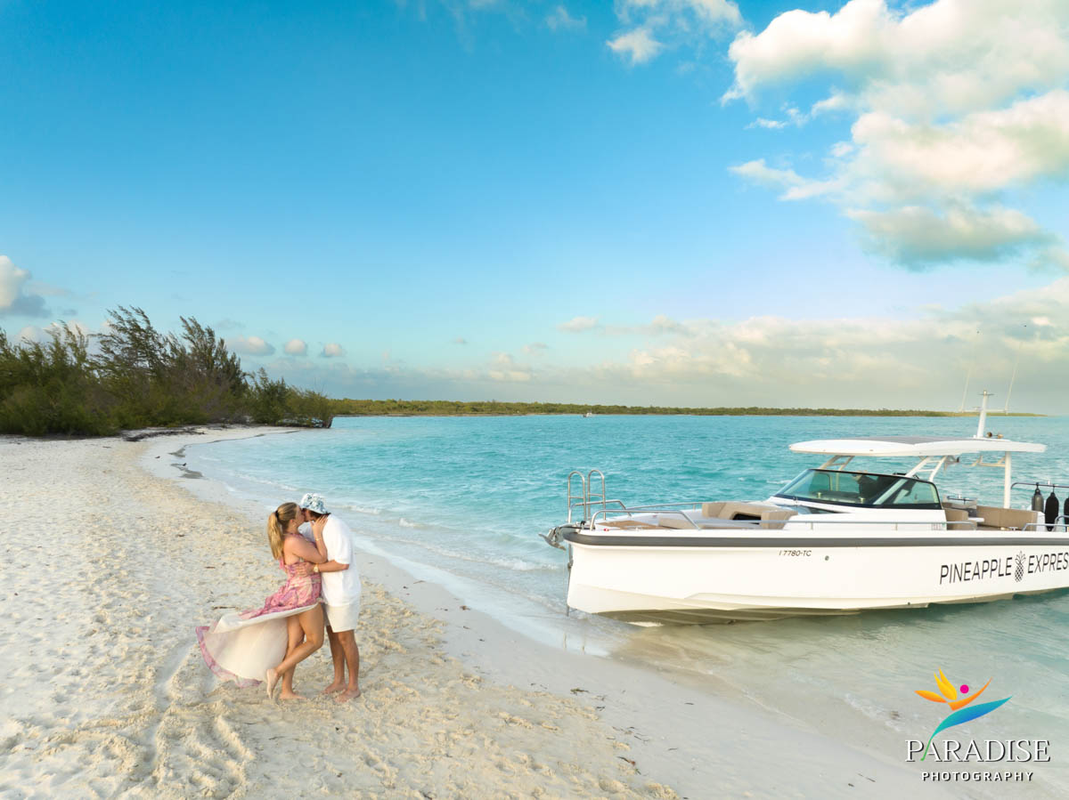 couple kiss on remote beach next to private boat