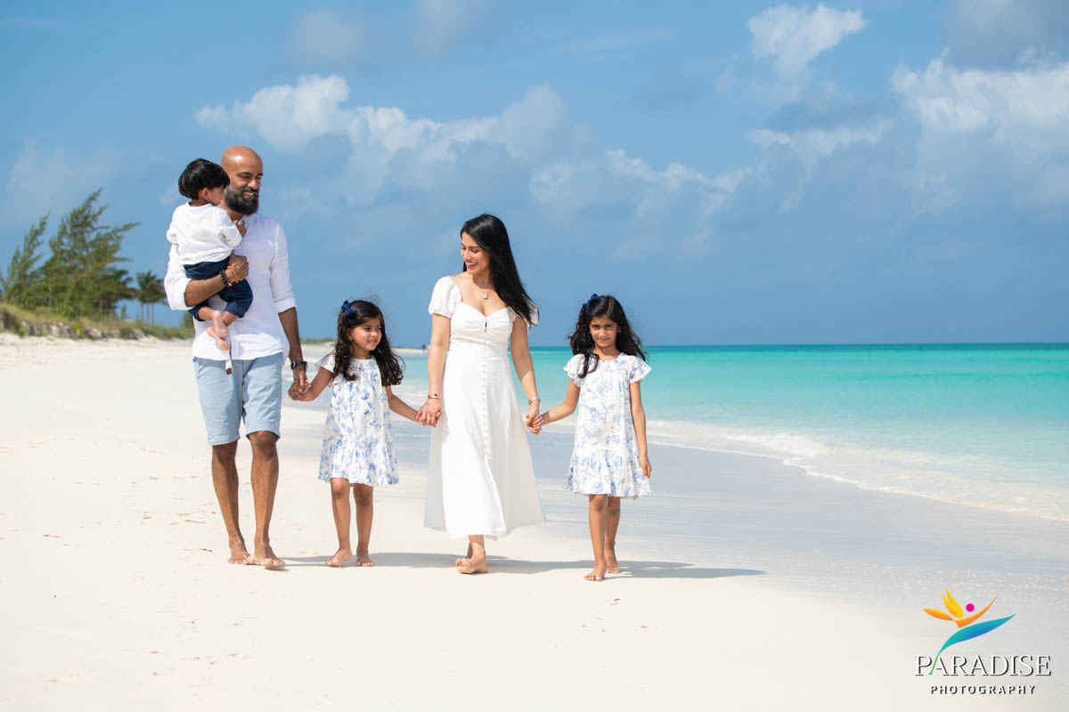 family walking along beautiful quiet beach with turquoise water