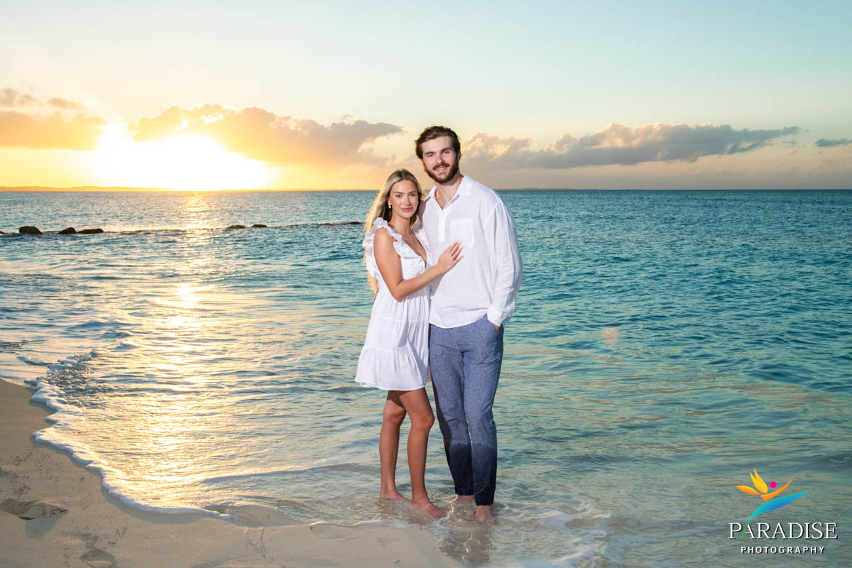 Couple standing in ocean at golden hour, wrapped in a warm embrace