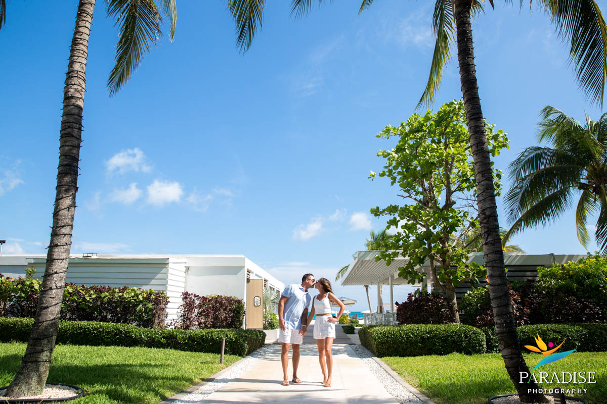 Couple posing playfully under palm trees at a luxury resort entrance