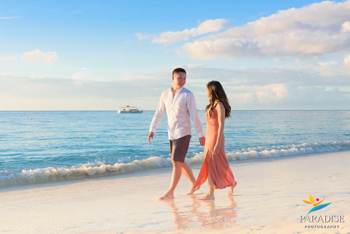Couple walking hand-in-hand barefoot at low tide with soft lighting