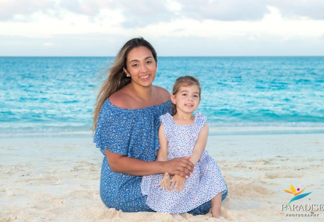 Mother and daughter sitting on Grace Bay beach smiling during Turks and Caicos vacation photo session.
