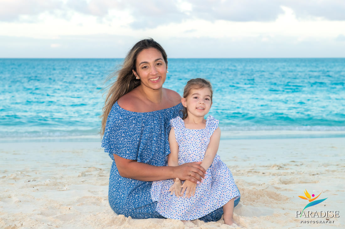 Mother and daughter sitting on Grace Bay beach smiling during Turks and Caicos vacation photo session.
