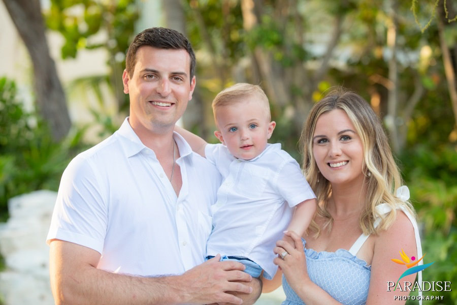 mom and dad holding little boy under the greens of the resort