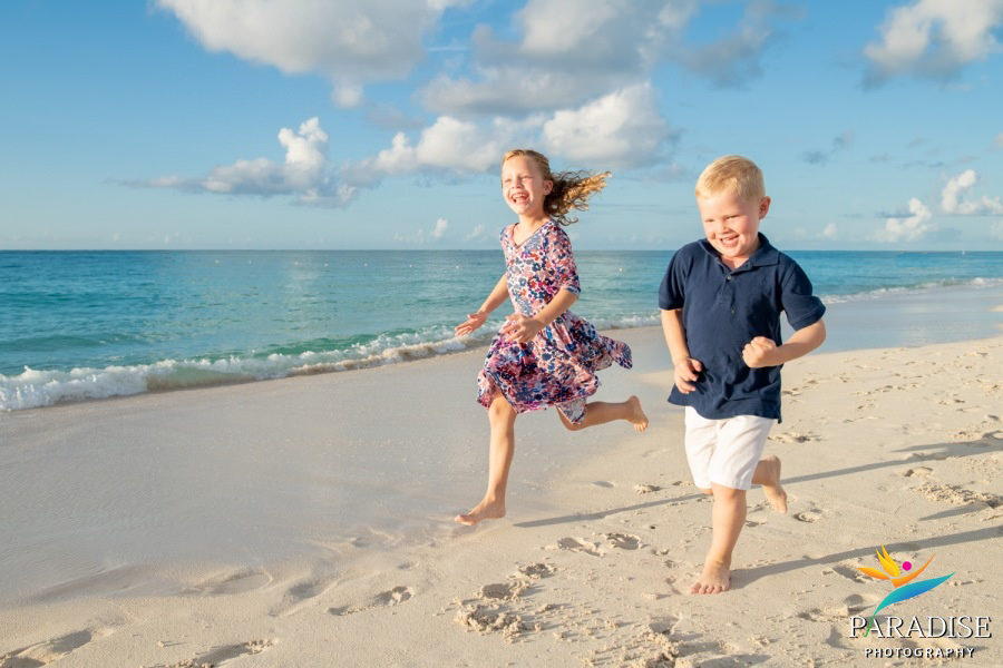 boy and girl running down the beach by the water