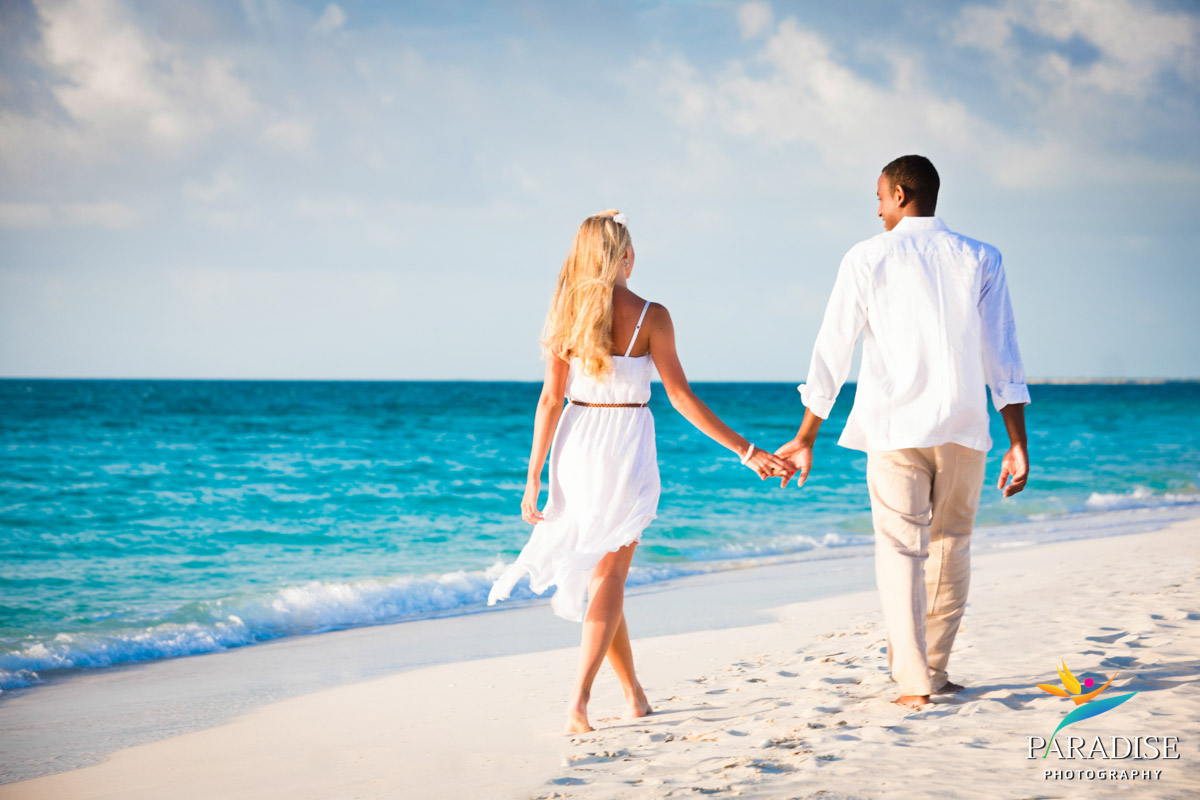 couple walking away holding hands on beach