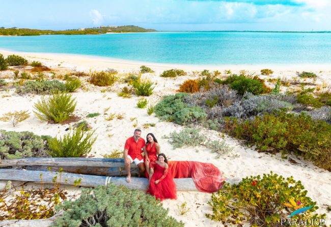 family in red sitting on rocks at the beach