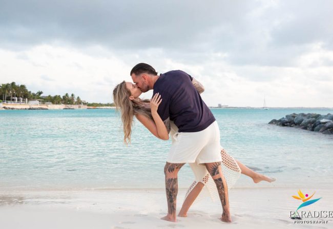 Couple happily looking at an engagement ring on the beach.