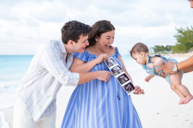 Side view portrait of husband and wife (in blue dress) smiling with their baby boy during family session at The Venetian.