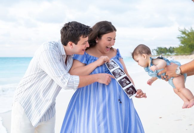 Side view portrait of husband and wife (in blue dress) smiling with their baby boy during family session at The Venetian.