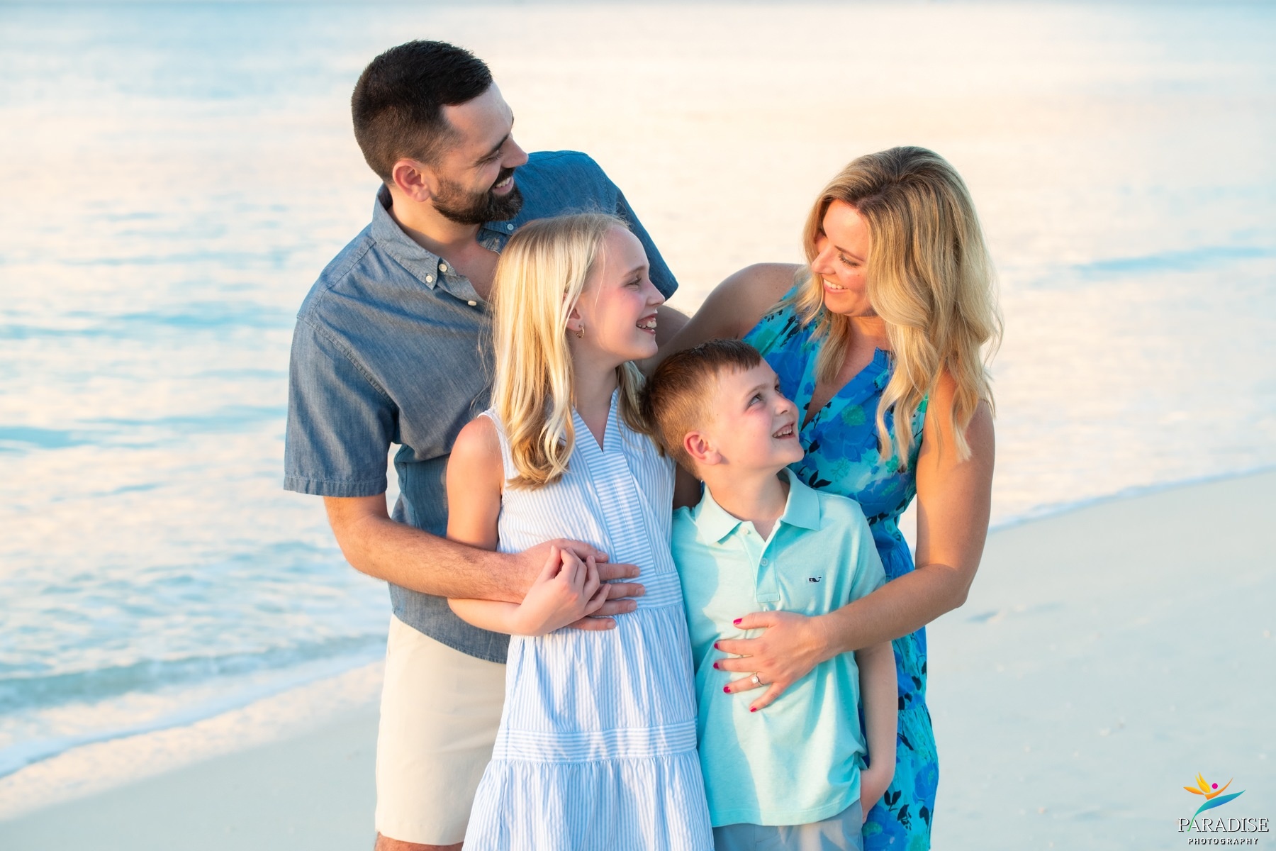 A beautiful family girl in a blue dress posing among sea oats on a sandy beach