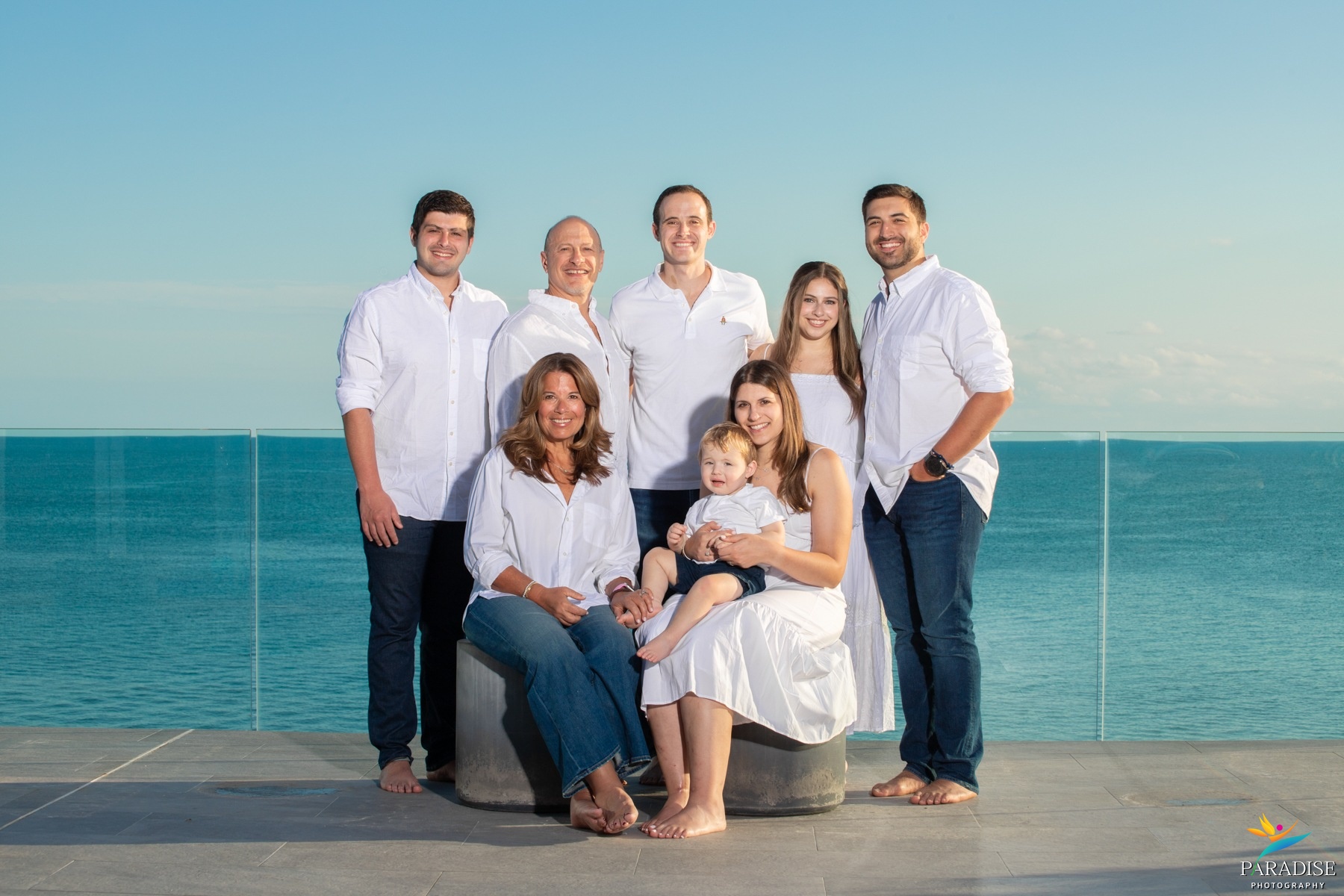 A beautiful family cuddled together in a warm portrait glowing in the beach sunset