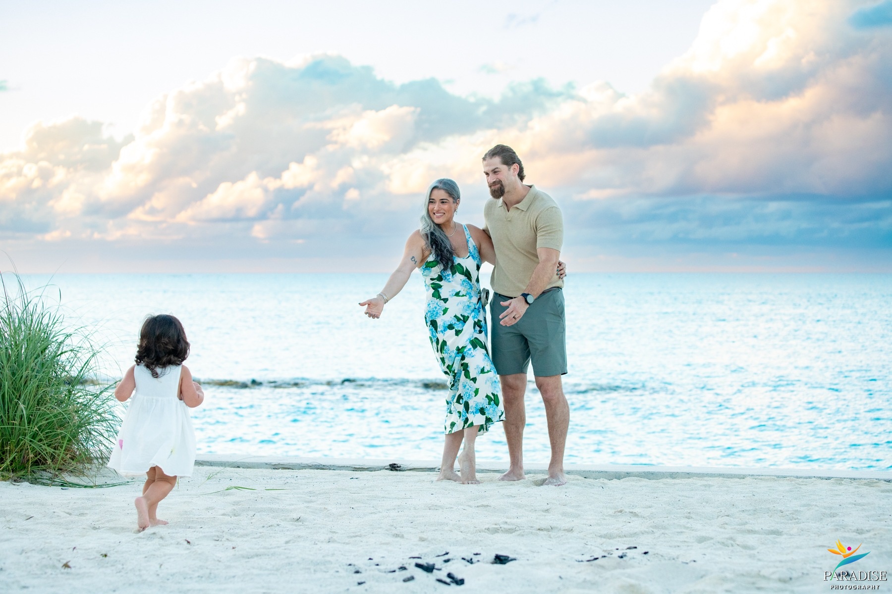 A beautiful family walking along the beach shore under a bright blue sky