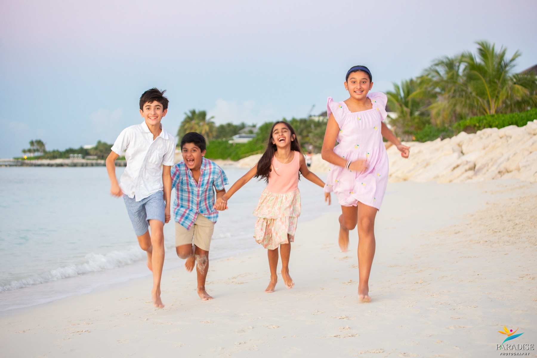 A beautiful family woman joyfully raising her arms at the ocean during a vivid sunset