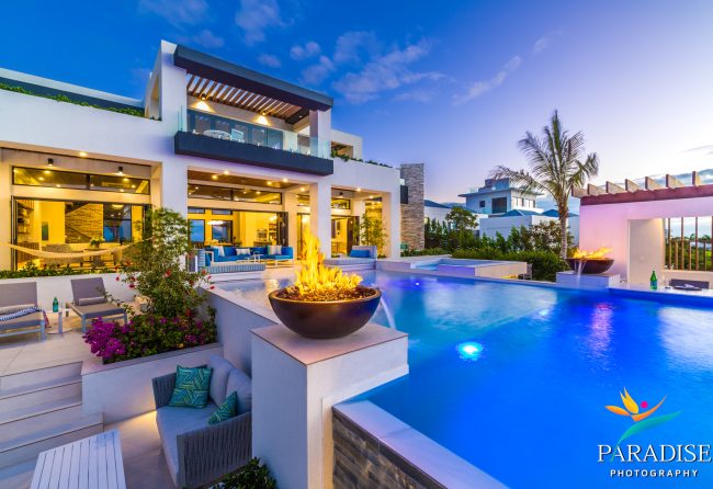 Providenciales luxury villa illuminated pool with fire bowl feature at evening dusk