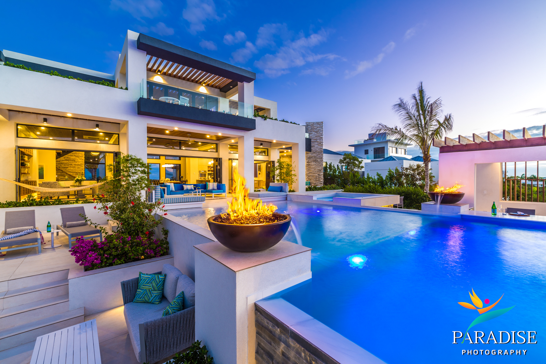 Providenciales luxury villa illuminated pool with fire bowl feature at evening dusk