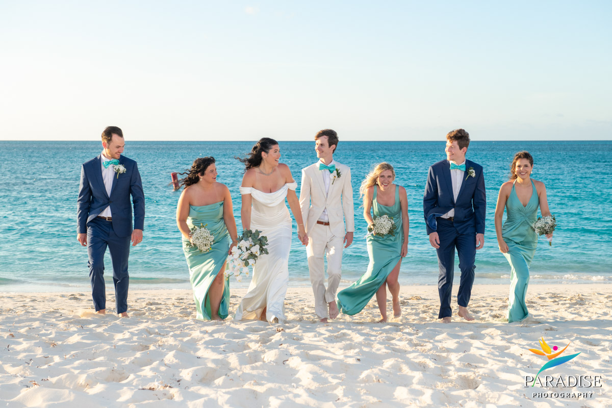 Bride, groom and wedding party walk along the beach in teal dresses at Ritz-Carlton Turks and Caicos