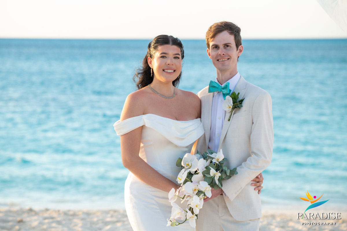 Smiling bride and groom by turquoise water at their Ritz-Carlton Turks and Caicos beach wedding