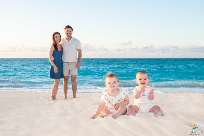 returning-clients-family-portraits-turks-caicos mom and dad watching the babies play in the sand by the ocean