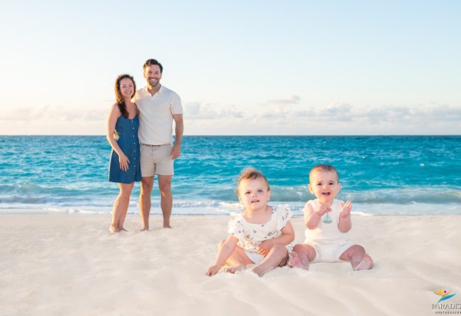 returning-clients-family-portraits-turks-caicos mom and dad watching the babies play in the sand by the ocean