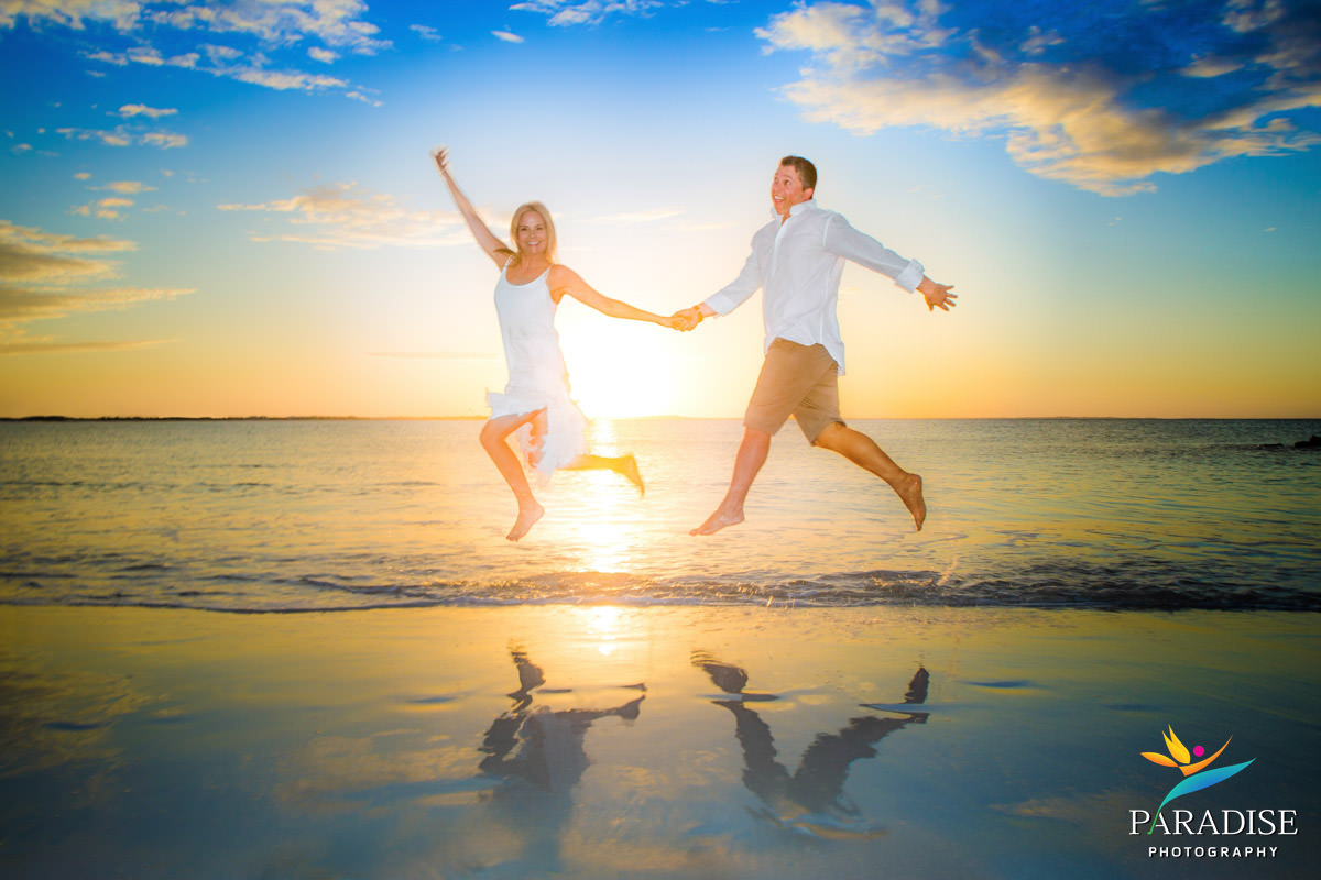 Couple jumping on the beach at sunset with reflection, captured by a Turks and Caicos couples photographer